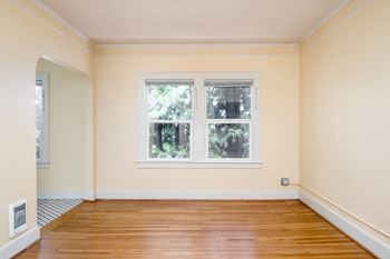 an empty room with two windows and a hardwood floor